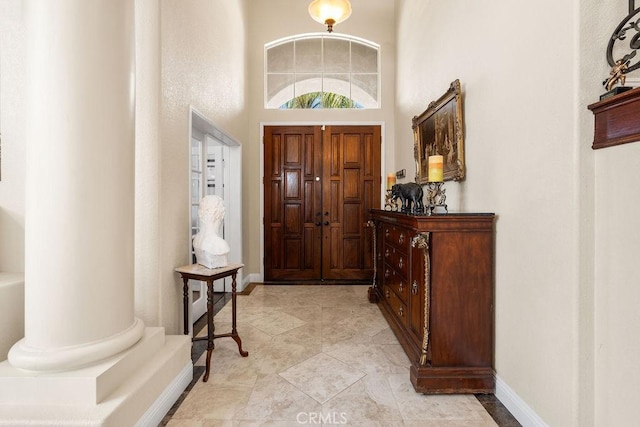 entryway with a towering ceiling and decorative columns