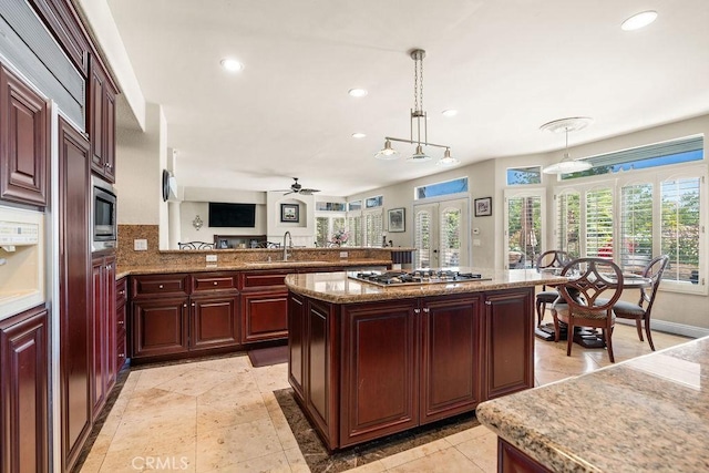 kitchen featuring ceiling fan, french doors, a center island, decorative light fixtures, and appliances with stainless steel finishes