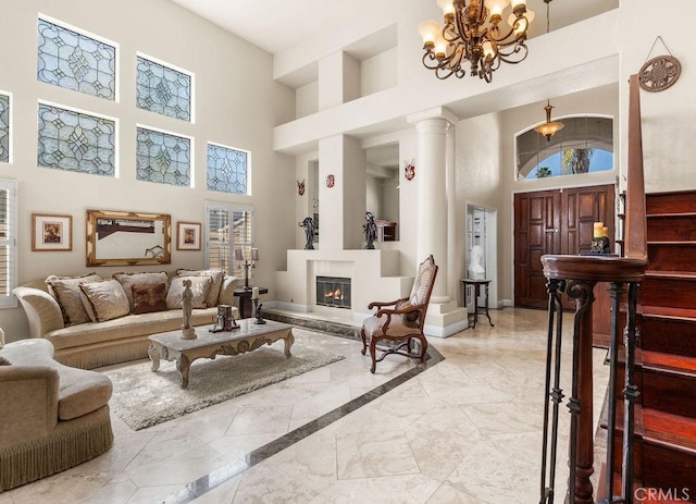 living room featuring a high ceiling, decorative columns, and a notable chandelier