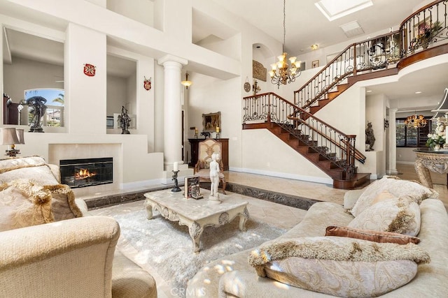 living room featuring a chandelier, a towering ceiling, and ornate columns