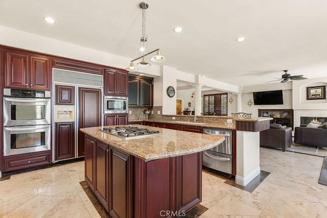 kitchen featuring kitchen peninsula, tasteful backsplash, ceiling fan, built in appliances, and decorative light fixtures