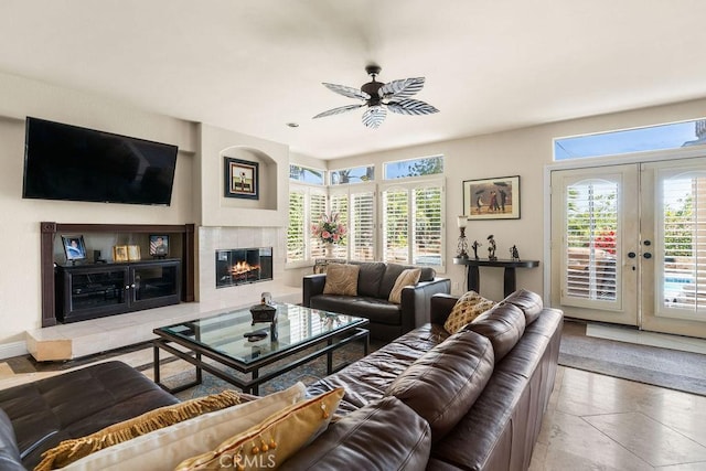 living room with tile patterned flooring, ceiling fan, french doors, and a tiled fireplace