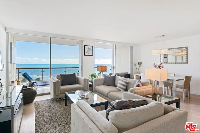 living room with a wall of windows, a water view, and hardwood / wood-style floors