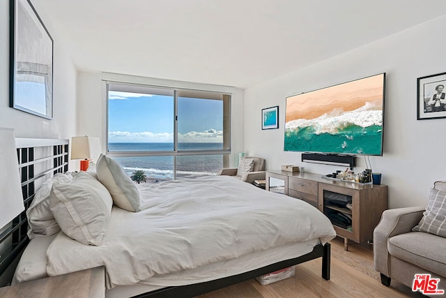 bedroom featuring a water view and light hardwood / wood-style flooring