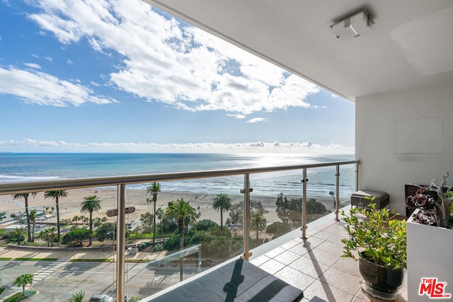 balcony featuring a view of the beach and a water view