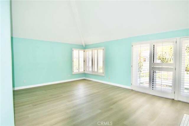 empty room featuring light wood-type flooring and lofted ceiling with beams