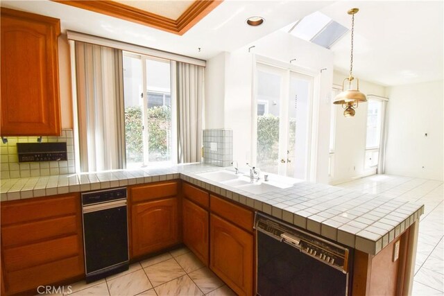 kitchen featuring black dishwasher, kitchen peninsula, pendant lighting, tile counters, and tasteful backsplash