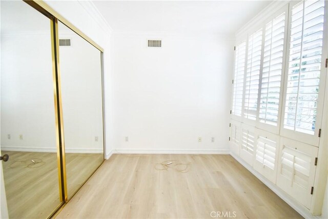 unfurnished bedroom featuring crown molding, a closet, and light hardwood / wood-style floors