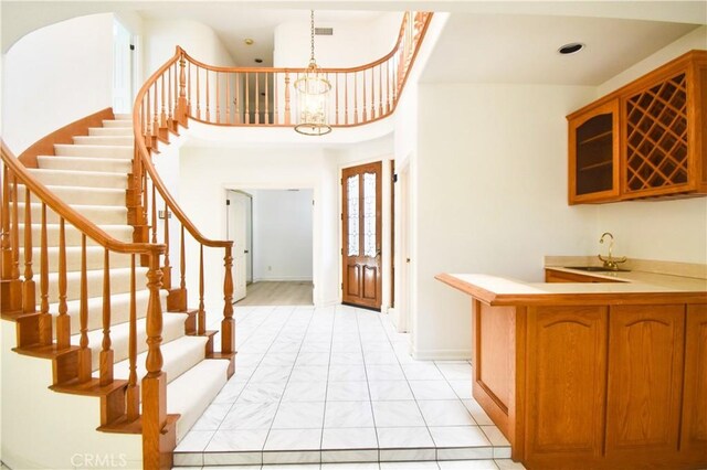 entryway with a towering ceiling, a chandelier, and sink