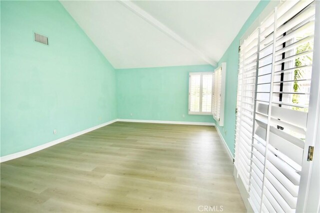 empty room featuring lofted ceiling, a healthy amount of sunlight, and hardwood / wood-style floors