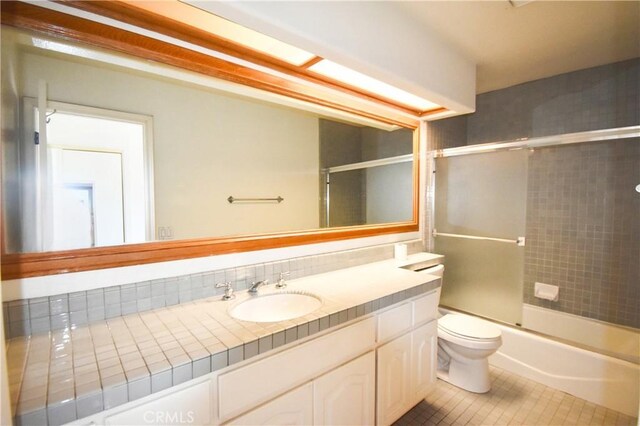 full bathroom with tile patterned floors, toilet, bath / shower combo with glass door, and vanity