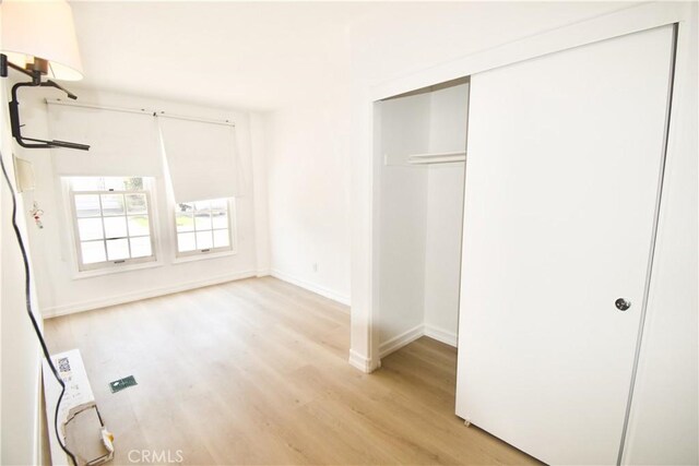 unfurnished bedroom with a closet and light hardwood / wood-style floors