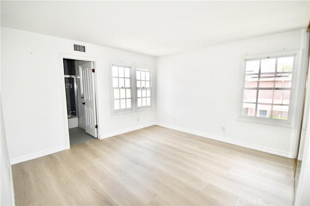 unfurnished bedroom with light wood-type flooring and connected bathroom