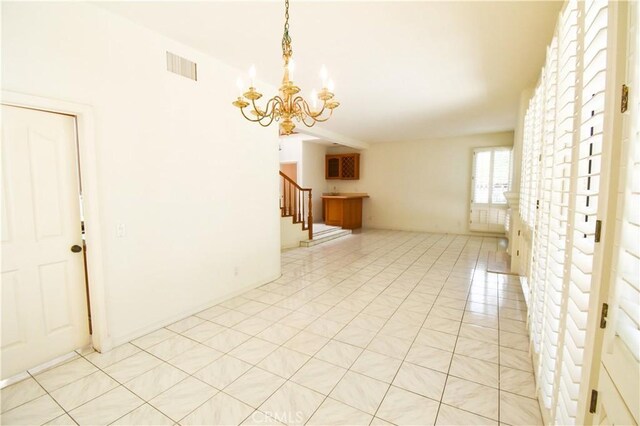 tiled empty room featuring an inviting chandelier