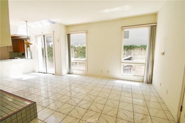 unfurnished living room with light tile patterned flooring and a healthy amount of sunlight