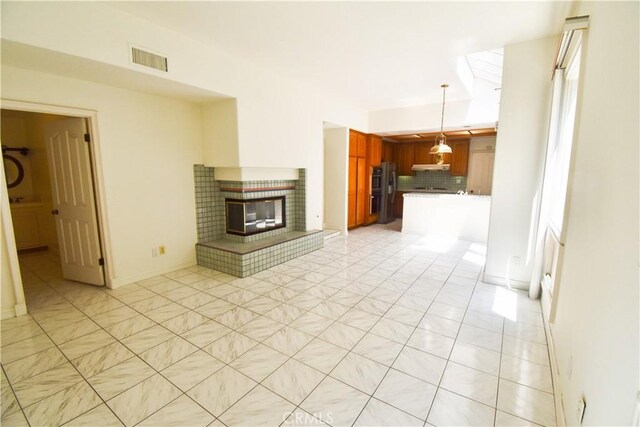 unfurnished living room featuring a tile fireplace and light tile patterned flooring