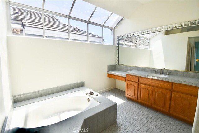 bathroom featuring tile patterned flooring, vanity, a relaxing tiled tub, and a wealth of natural light