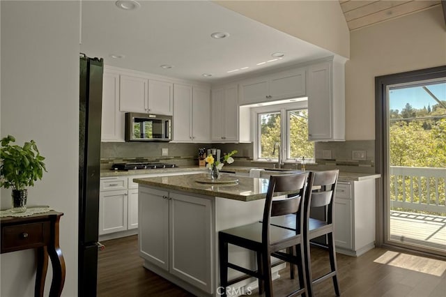 kitchen featuring white cabinets, a healthy amount of sunlight, a kitchen island, and appliances with stainless steel finishes