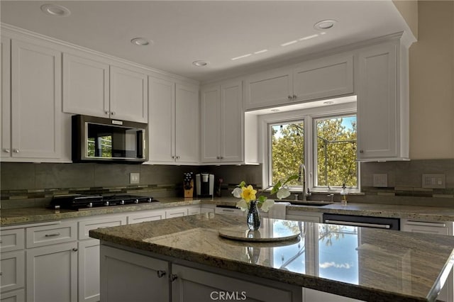 kitchen with backsplash, stone counters, white cabinetry, and stainless steel appliances