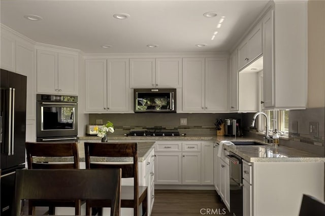 kitchen with light stone countertops, sink, black appliances, dark hardwood / wood-style floors, and white cabinetry