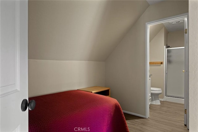 bedroom featuring light wood-type flooring, connected bathroom, and vaulted ceiling