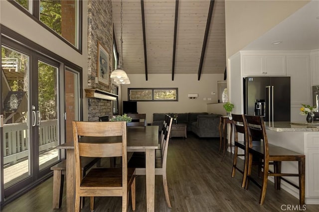 dining space with plenty of natural light, dark hardwood / wood-style floors, a stone fireplace, and high vaulted ceiling