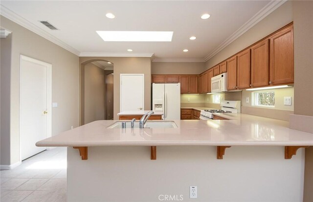 kitchen with a kitchen bar, white appliances, crown molding, and sink