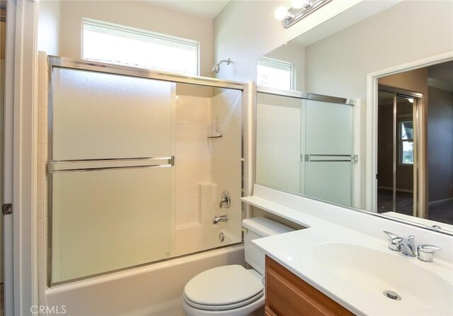 full bathroom with combined bath / shower with glass door, vanity, and toilet