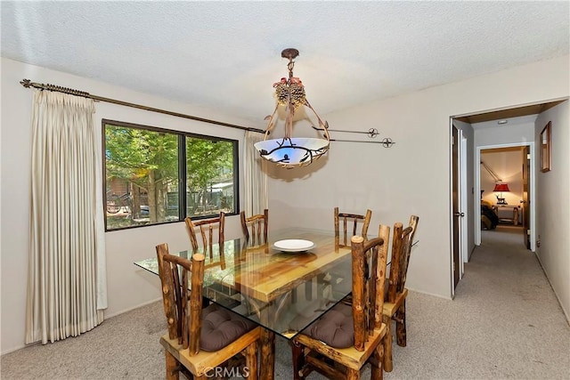 dining area featuring a textured ceiling and light carpet