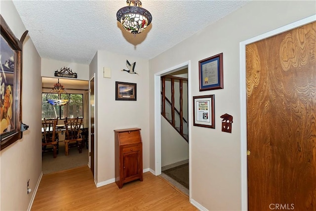 hallway featuring a textured ceiling and light hardwood / wood-style flooring