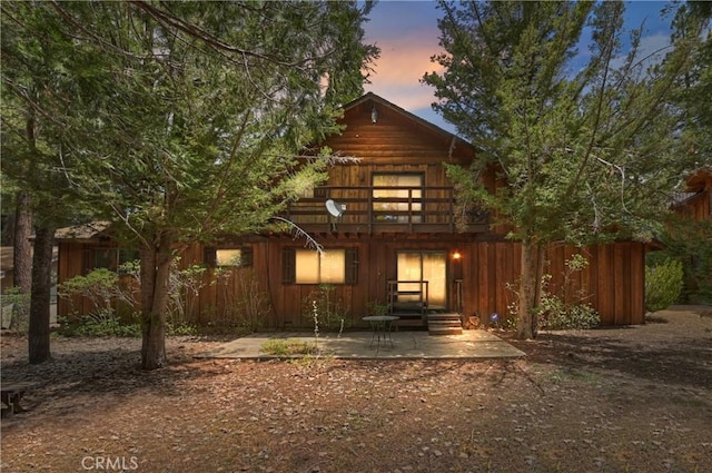 back house at dusk featuring a patio area