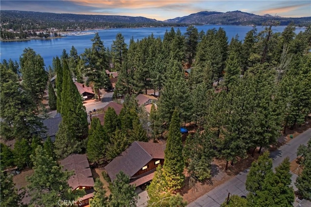 aerial view at dusk featuring a water and mountain view