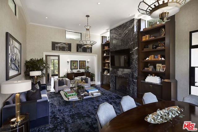 living room with crown molding, a fireplace, and built in features