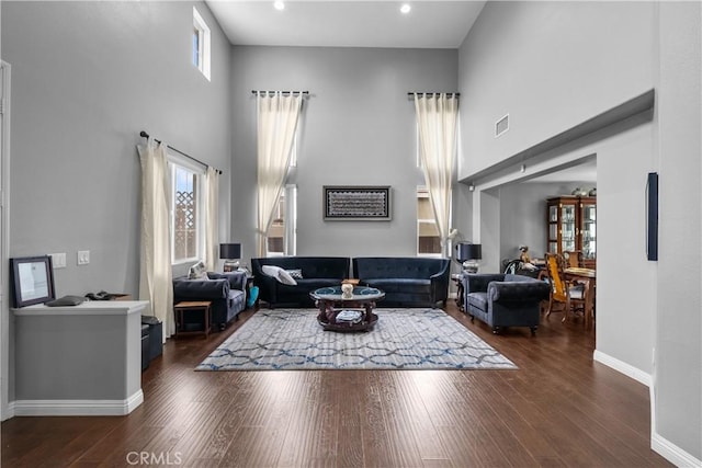 living room with dark hardwood / wood-style floors and a towering ceiling