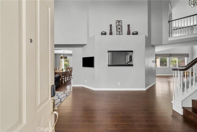 living room with dark hardwood / wood-style floors, a towering ceiling, and a wealth of natural light