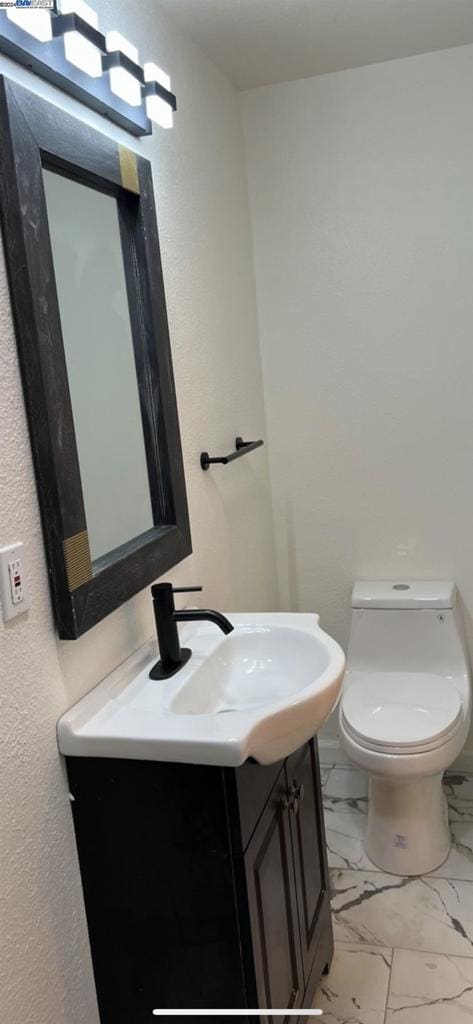 bathroom featuring tile flooring, vanity, and toilet