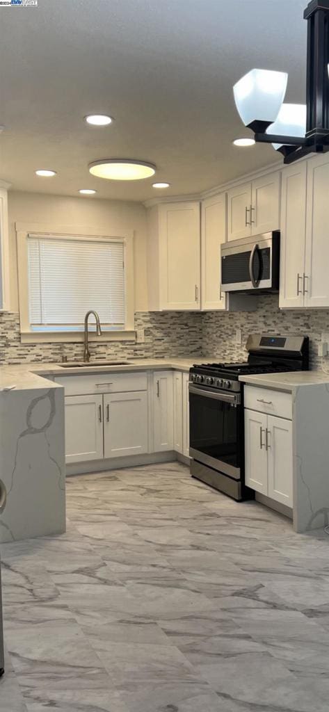 kitchen featuring appliances with stainless steel finishes, white cabinetry, sink, and tasteful backsplash