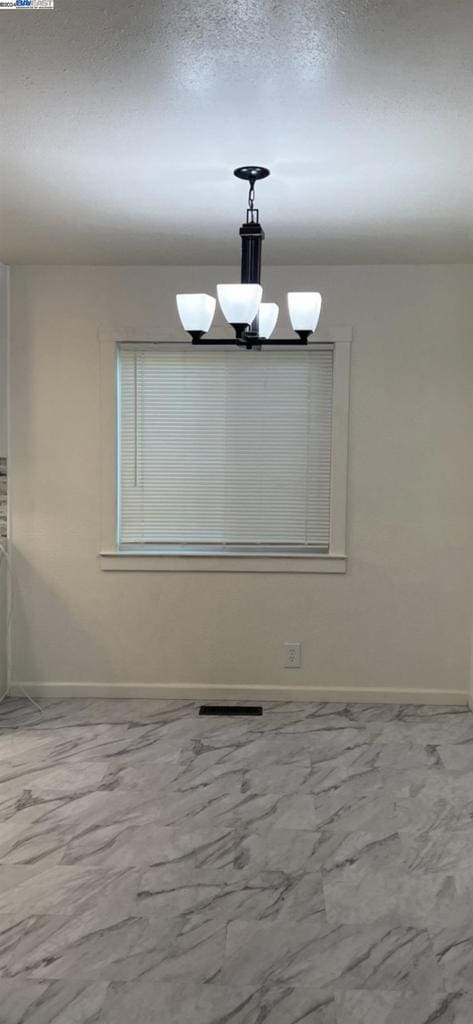 unfurnished room with a notable chandelier and a textured ceiling