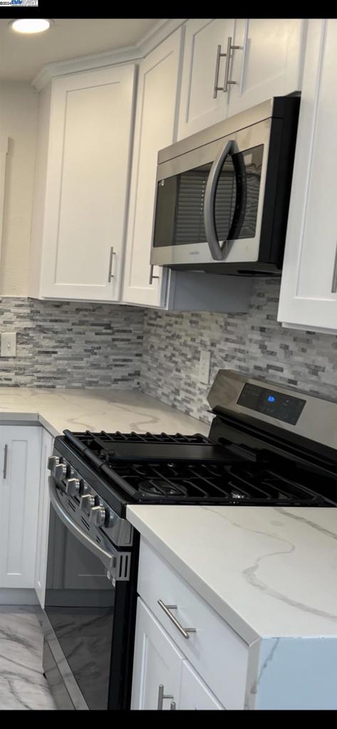 kitchen with white cabinets, tasteful backsplash, and stainless steel appliances