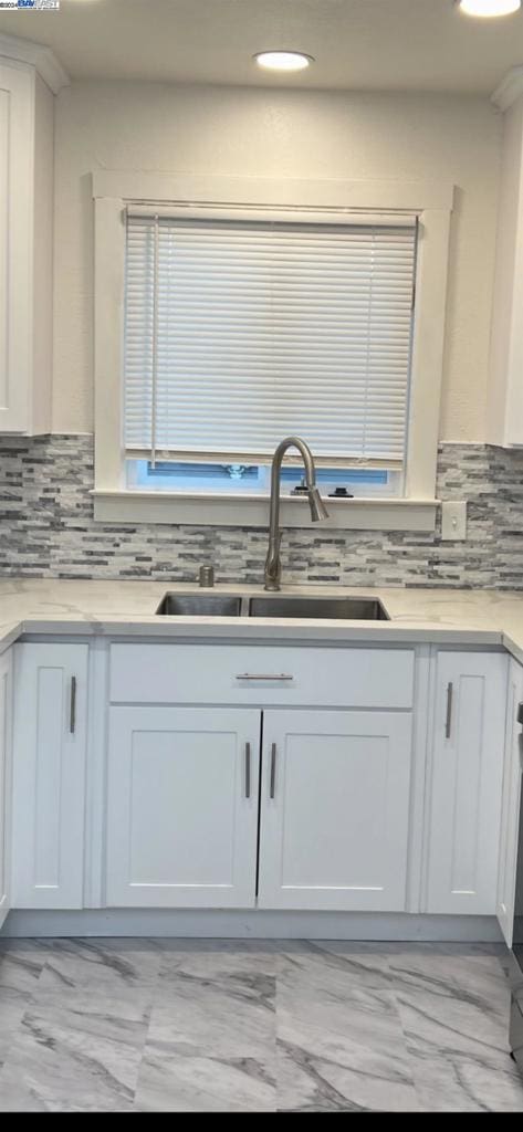 kitchen with backsplash, sink, and white cabinetry