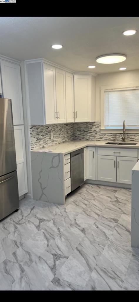 kitchen with backsplash, appliances with stainless steel finishes, sink, and light tile floors