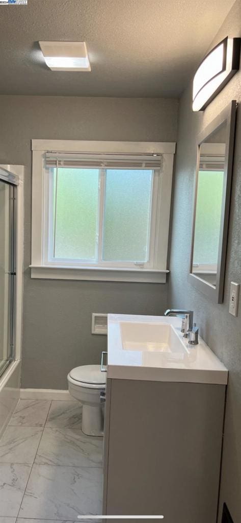 bathroom featuring tile flooring, plenty of natural light, vanity, and toilet