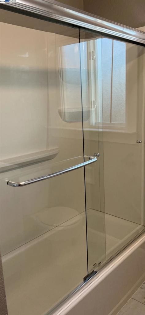 bathroom featuring tile floors and bath / shower combo with glass door