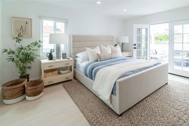 bedroom with access to outside, light wood-type flooring, and multiple windows