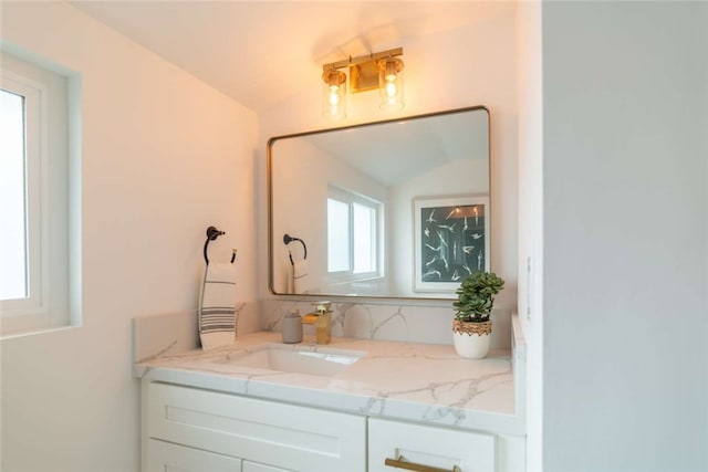 bathroom with plenty of natural light, vanity, and lofted ceiling