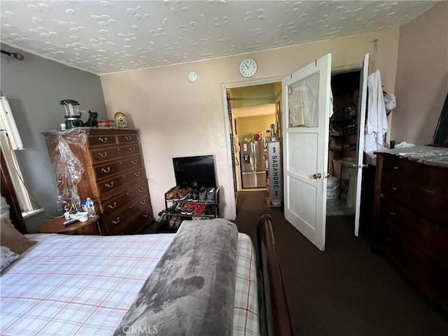 bedroom with a textured ceiling and stainless steel refrigerator with ice dispenser