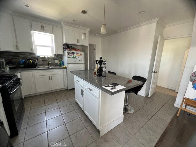 kitchen featuring a sink, gas stove, freestanding refrigerator, light tile patterned floors, and tasteful backsplash