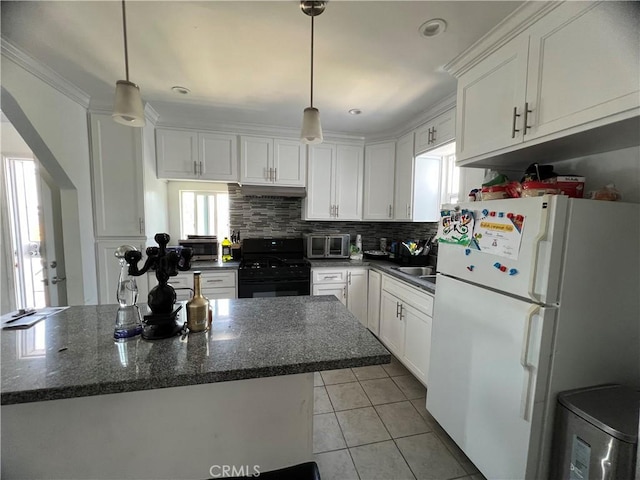 kitchen with white cabinets, black gas stove, freestanding refrigerator, light tile patterned floors, and tasteful backsplash