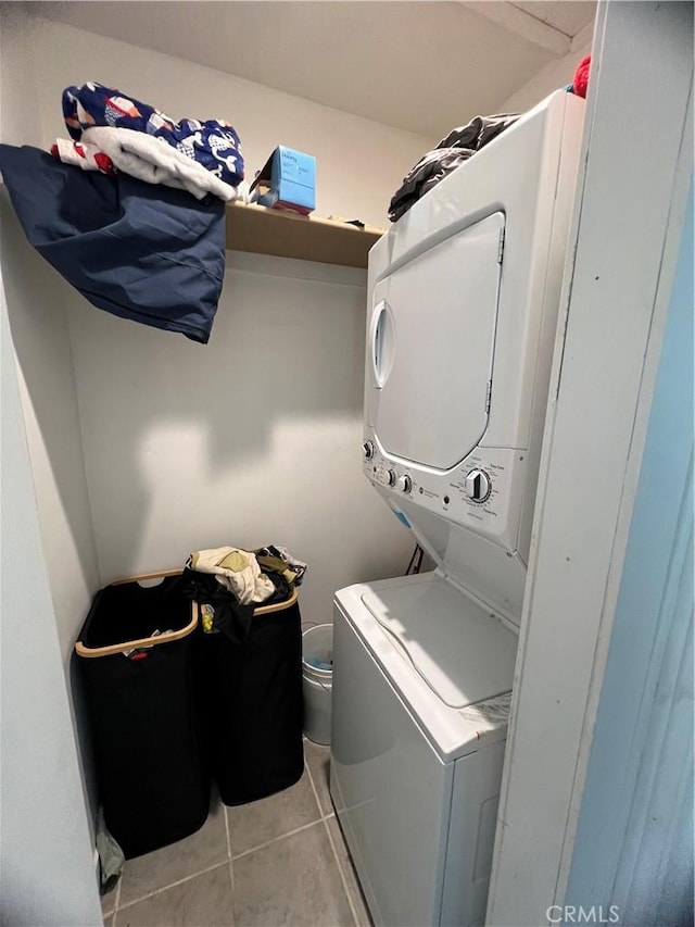 laundry room featuring laundry area, stacked washing maching and dryer, and light tile patterned flooring
