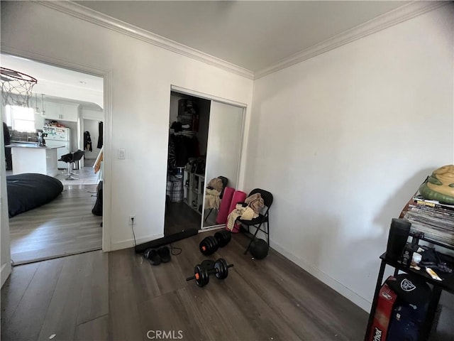 interior space with crown molding, baseboards, a closet, and wood finished floors